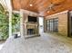 Covered outdoor patio featuring brick floors, fireplace, ceiling fan, and mounted television for year-round enjoyment at 825 Hudson Pl, Davidson, NC 28036