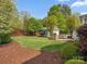 Spacious backyard with mature trees, landscaping, detached garage, stone patio, and green lawn at 894 Stratford Run Dr, Fort Mill, SC 29708