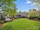 Expansive backyard with mature trees, landscaping, stone patio, and covered porch, perfect for outdoor living at 894 Stratford Run Dr, Fort Mill, SC 29708