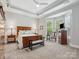 Spacious bedroom with a sitting area, tray ceiling, large window and wood furniture at 894 Stratford Run Dr, Fort Mill, SC 29708
