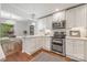 Kitchen featuring stainless steel appliances, including a double oven, white cabinets, a marble countertop and hardwood floors at 9012 Saint Thomas Ln, Charlotte, NC 28277