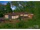 Stunning elevated home with a brick facade, modern gray siding, and large windows surrounded by lush greenery at 916 E Park Dr, Lincolnton, NC 28092