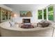Bright living room with a unique rounded sofa, fireplace, and large windows showcasing the outdoor greenery at 916 E Park Dr, Lincolnton, NC 28092