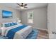 Virtually staged bedroom with neutral walls, blue bedding, wood floors, and bright natural light at 112 Cleveland Ave, Albemarle, NC 28001