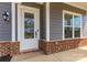 Charming home entrance features a white door with glass and decorative wreath, brick accents and a cozy light fixture at 1358 Cedardale Ln, Denver, NC 28037