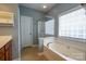 Bright bathroom features a tub, tiled shower, and large window at 13936 Mallard Lake Rd, Charlotte, NC 28262