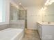 Bright bathroom featuring a soaking tub, glass shower, double sinks, and tile flooring at 1516 Laggan Ln, Indian Trail, NC 28079