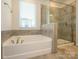 Bathroom features a bathtub, enclosed glass shower, and a window at 1516 Laggan Ln, Indian Trail, NC 28079