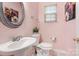 Powder room features pedestal sink, floral artwork, toilet and natural light at 16219 Long Talon Way, Charlotte, NC 28273