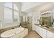 Bright bathroom featuring a soaking tub under a large window and a glass-enclosed shower at 2001 Arundale Ln, Matthews, NC 28104