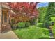 Landscaped front yard with a vibrant maple tree, lush lawn, and brick accents at 2001 Arundale Ln, Matthews, NC 28104
