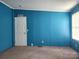 Bedroom with teal walls, carpet flooring, one window, and a white door at 234 Olin Loop, Olin, NC 28660