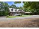 Side view of brick home with metal roof, dormers, and a covered carport surrounded by lush greenery at 32060A Flint Ridge Rd, Albemarle, NC 28001