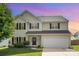 Two-story home with black shutters, fresh green lawn and a two car garage under a pink and purple sky at 407 Goodloe Dr, Charlotte, NC 28262