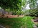 Spacious backyard with manicured lawn, mature trees, and play set at 5412 Crosshill Ct, Charlotte, NC 28277