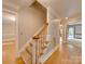 Inviting staircase with carpeted steps, hardwood floors, and a wooden banister at 5412 Crosshill Ct, Charlotte, NC 28277