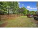Large backyard with a wooden fence, grassy area, and a deck, ideal for outdoor activities at 5524 Wyalong Dr, Charlotte, NC 28227