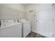 Efficient laundry room with white washer, dryer, overhead shelving, and white door for storage at 5524 Wyalong Dr, Charlotte, NC 28227