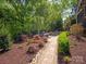 Landscaped backyard featuring a brick path, fire pit and manicured shrubs at 5809 Woodleigh Oaks Dr, Charlotte, NC 28226