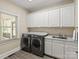 Bright laundry room with gray washer and dryer and white cabinetry at 5809 Woodleigh Oaks Dr, Charlotte, NC 28226