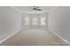 Spacious bedroom featuring neutral carpet, gray walls, white trim, and three windows providing natural light at 7005 Camrose Crossing Ln, Matthews, NC 28104