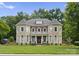 Elegant stone and brick home featuring a manicured lawn, grand entrance, and mature trees at 7005 Camrose Crossing Ln, Matthews, NC 28104
