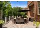 Outdoor dining space on a wooden deck, with an umbrella, brick exterior, and green surroundings at 7005 Camrose Crossing Ln, Matthews, NC 28104