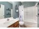 Clean bathroom with blue walls, shower-tub combo, floral curtain, and oak vanity sink at 9904 Rocky Ford Club Rd, Charlotte, NC 28269