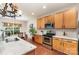 Bright kitchen with stainless steel appliances, wood cabinets, and white countertops, connecting to an adjacent dining area at 9904 Rocky Ford Club Rd, Charlotte, NC 28269