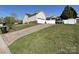 View of the home's exterior, featuring a two-car garage, vinyl siding, and a long driveway with ample parking at 1009 Preston Dr, Lowell, NC 28098