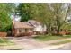 Charming home with a brick chimney, colorful flower beds, and a spacious front yard surrounded by mature trees at 1114 Hartford Ave, Charlotte, NC 28209