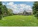 Expansive backyard with lush green lawn, patio and beautiful home exterior under a partly cloudy sky at 115 Ladybug Ct, Statesville, NC 28625
