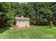 Charming backyard shed with double doors, surrounded by a lush green lawn and mature trees at 115 Ladybug Ct, Statesville, NC 28625