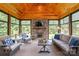 Inviting sunroom with wood paneled vaulted ceilings, stone fireplace, and comfortable seating arrangement at 115 Ladybug Ct, Statesville, NC 28625