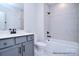 Well-lit bathroom featuring gray vanity, white fixtures, tiled walls, and combo tub-shower at 122 Huntcliff Dr, Statesville, NC 28677