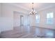 Elegant dining room with wainscoting, light hardwood floors, modern chandelier, and bright natural light at 122 Huntcliff Dr, Statesville, NC 28677