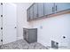 Convenient laundry room with gray cabinets, sink, and patterned tile flooring at 122 Huntcliff Dr, Statesville, NC 28677