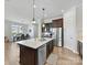 A modern kitchen features an island with a sink, stainless steel appliances, and a view of the dining area at 13702 Jacks Ln, Pineville, NC 28134