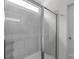 Modern walk-in shower with gray tiling, a glass door, and natural light from the window at 197 Park View Dr, Stanfield, NC 28163