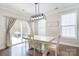 A dining room with a white table, chairs, a modern light fixture and sliding glass doors leading to the outside at 2014 Burton Point Ct, Waxhaw, NC 28173