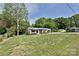 Home exterior featuring a well-manicured lawn, mature trees, and a charming covered front porch at 202 Hickory St, Locust, NC 28097