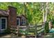 View of the rear exterior featuring a brick chimney, fenced yard, and lush green surroundings at 211 W Tennessee Ave, Bessemer City, NC 28016