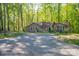 Exterior view of the home from the driveway surrounded by lush greenery and tall trees at 211 W Tennessee Ave, Bessemer City, NC 28016
