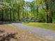 Wide shot of the home's exterior showcasing its setting amidst a lush, wooded landscape and long driveway at 211 W Tennessee Ave, Bessemer City, NC 28016