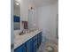 Bright bathroom featuring dual sinks, blue cabinets, decorative gold hardware, and tiled floors at 2380 Fairport Se Dr, Concord, NC 28025