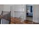 Upstairs hallway with wood floors, metal railings and view into a bedroom with blue curtains at 2380 Fairport Se Dr, Concord, NC 28025