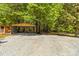 Gravel parking area with a large metal carport surrounded by mature trees at 4110 Charles Raper Jonas Hwy, Alexis, NC 28006