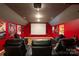 Home theater room with red walls, plush seating, and a large projection screen for entertainment at 4607 Bonroi Ave, Charlotte, NC 28213