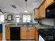 Kitchen area featuring granite countertops, stainless steel sink, black appliances, and light wood cabinets at 5304 Silabert Ave, Charlotte, NC 28205