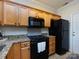 Kitchen with light wood cabinets, granite countertops, and black appliances including a microwave and refrigerator at 5304 Silabert Ave, Charlotte, NC 28205